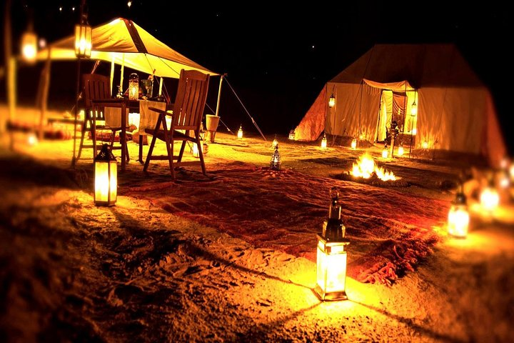 Experience the magic of the desert night with lanterns illuminating cozy camp seating inviting travelers to share stories under a blanket of stars while enjoying authentic Arabian hospitality.